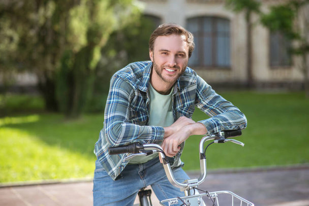 A picture of a young man in aplaid shirt on a bike - Foto, Imagen
