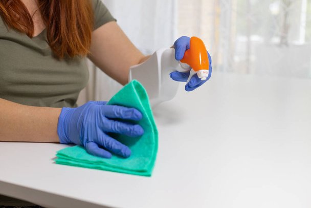 白いテーブルを掃除し、消毒剤の抗菌スプレーボトルでテーブル表面を消毒し、タオルや手袋で表面を洗浄します。COVID-19内部の消毒防止 - 写真・画像