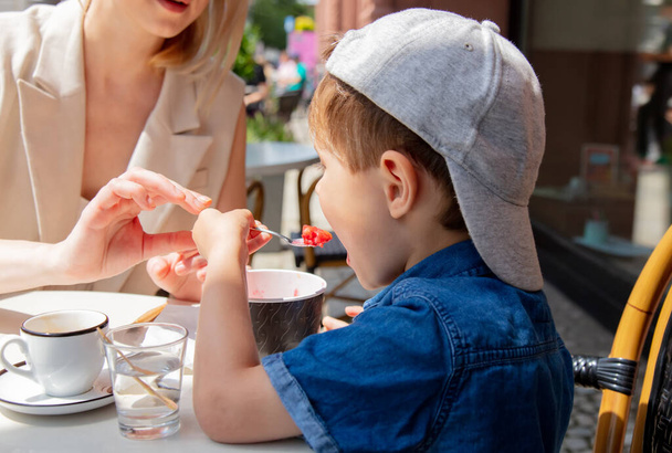 Äiti pojan kanssa kahvilassa lomalla Wroclawissa, Puolassa. Poika syö jäätelöä. - Valokuva, kuva