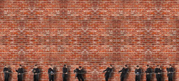 Team competing in tug of war. While some strive and do their duty, others are inattentive and delegate the work to others. Background of red bricks wall - Photo, Image