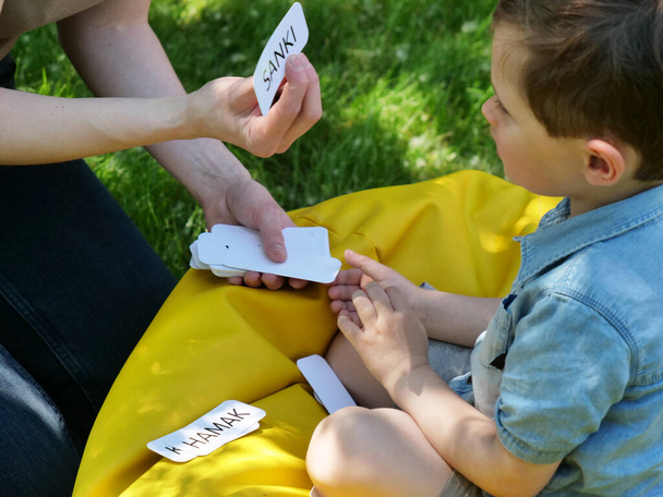 mamá enseña a pronunciar palabras usando la técnica Doman para un niño autista en el patio - Foto, Imagen