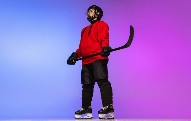 Retrato de vista inferior de longitud completa del jugador profesional de hockey femenino, en uniforme especial aislado sobre fondo azul púrpura degradado. - Foto, imagen