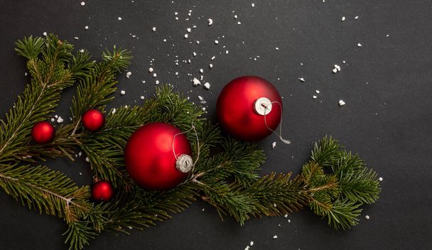 クリスマスの装飾。黒の背景に赤いクリスマスの泡と新鮮なモミの小枝、冬の休日の装飾、クローズアップビュー. - 写真・画像