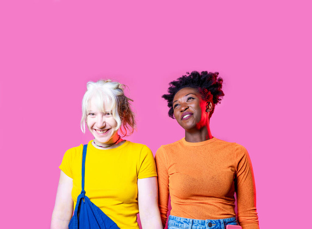 Two young diverse multicultural caucasian and black women best friends posing isolated background having fun laughing - Photo, Image