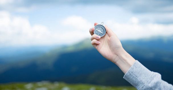 Traveler hand holds a compass on the beautiful Carpathian mountains view. Horizontal banner with place for text. Vacation and travel. - Photo, Image