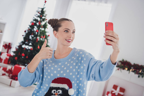 Portrait of attractive cheerful girl blogging making selfie showing thumbup winter day eve tradition at home indoors - Foto, Imagem