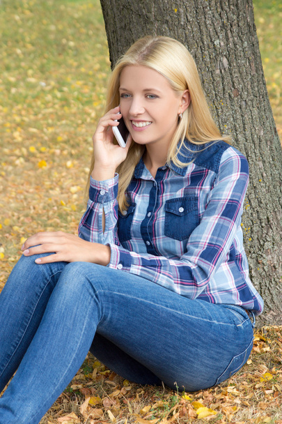 Retrato de mujer hermosa sentada en el parque otoño y usando pho - Foto, imagen