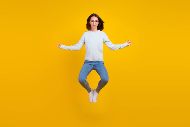 Full body photo of happy calm young woman jump wear glasses asana isolated on yellow color background - Фото, изображение