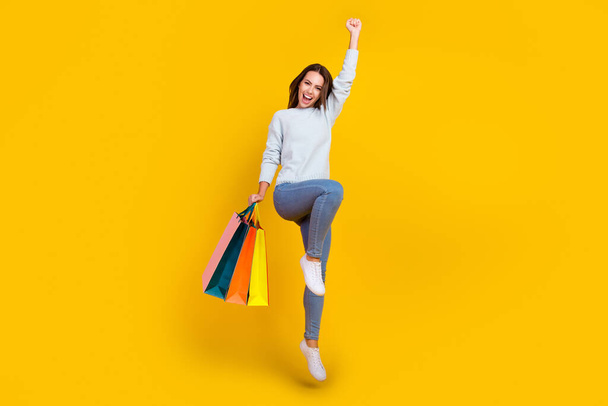 Full length photo of brown haired stylish woman jump winner sale hold bag shopper isolated on yellow color background - Foto, Imagem