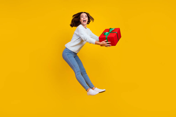 Full body photo of amazed positive young woman jump up gift celebrate get isolated on yellow color background - Zdjęcie, obraz