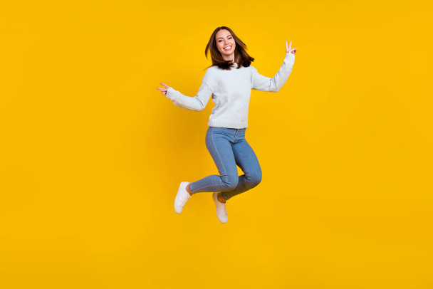 Full size photo of cheerful positive cool young woman jump up make v-signs sale isolated on yellow color background - Foto, Bild