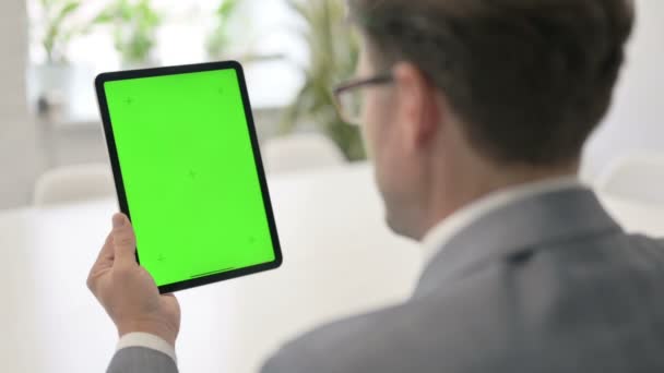 Man op zoek naar tablet met groene chroma scherm  - Video