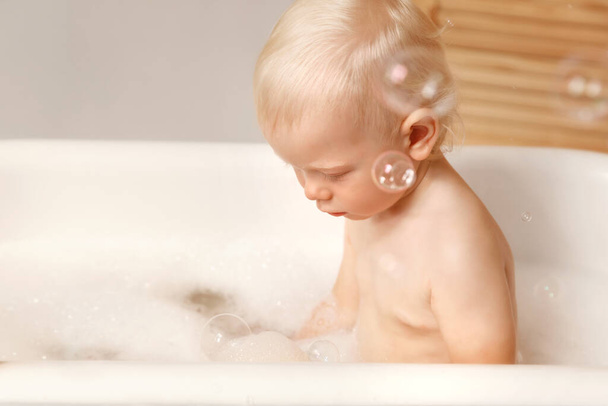 Baby sitting in the bath and looking at the water. - Φωτογραφία, εικόνα