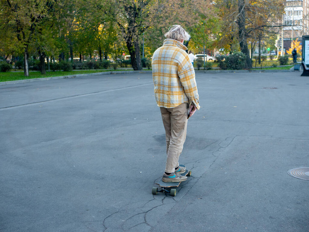 男はモスクワの通りでスケートボードに乗っている。秋の朝. - 写真・画像