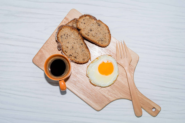 fatia de pão de ovo frito na tábua de corte tem café expresso isolado no fundo branco de perto, vista superior, conceito de comida e bebida de café da manhã. - Foto, Imagem