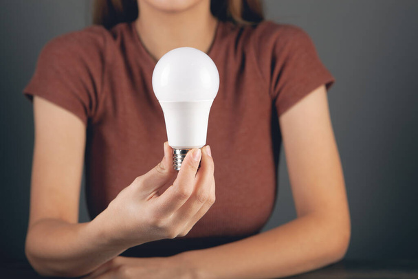 young woman holding a light bulb - Фото, изображение