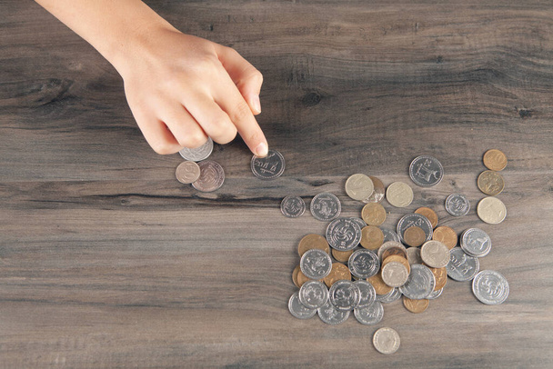 vrouw die munten telt op tafel - Foto, afbeelding