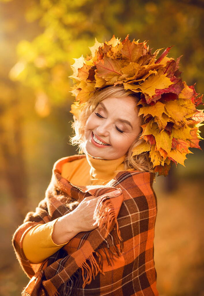 幸せな高齢者。公園を歩いていると、黄色の秋の葉を持つ陽気な高齢者の女性の肖像画. - 写真・画像
