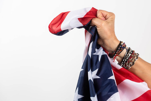 Рука женщины крепко держит флаг Америки. На белом фоне - Фото, изображение