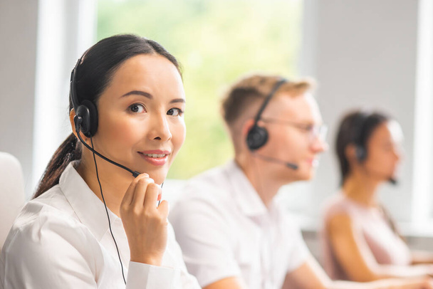 Diverse team of young professionals is working in the phone support office. Working day of sales managers in the call center. Business, telephone consulting and problem solving. - Foto, imagen