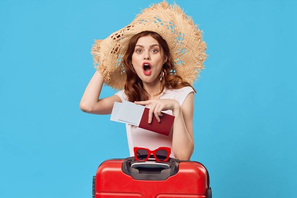 kobieta z czerwoną walizką siedzi na podłodze niebieski tło podróży wakacje - Zdjęcie, obraz
