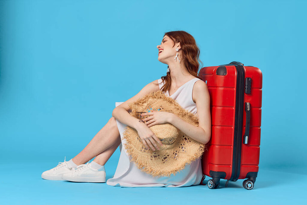 γυναίκα με καπέλο κόκκινη βαλίτσα διακοπές πτήση αεροδρόμιο μπλε φόντο - Φωτογραφία, εικόνα