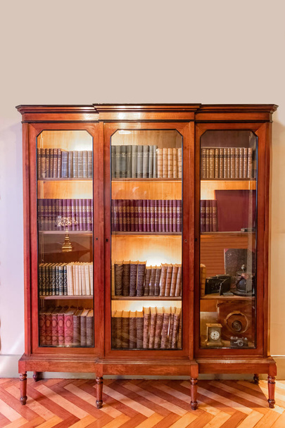 An old bookcase with books and glass doors  - Photo, Image