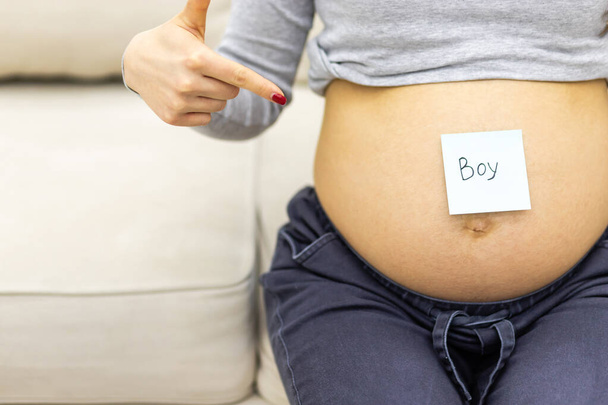 Cropped photo of female abdomen with written word boy on the paper. - Φωτογραφία, εικόνα