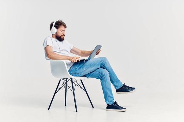 joven sentado en una silla con un ordenador portátil en auriculares entretenimiento - Foto, Imagen