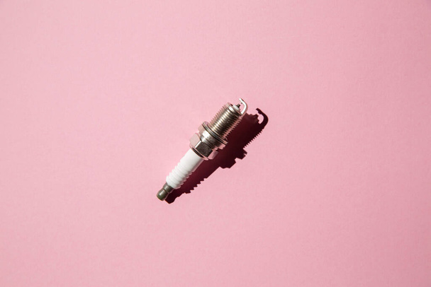 Spark plug. Car candle lies against a pink background. Auto engine electrician - 写真・画像