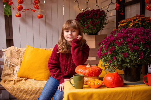 little girl with pumpkin in autumn in the garden near the house - Photo, Image