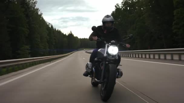 Ember lovaglás zavaró motorkerékpár az autópályán az erdőn keresztül, elölnézet - Felvétel, videó