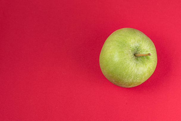 Kırmızı arkaplanda yeşil elma - Fotoğraf, Görsel