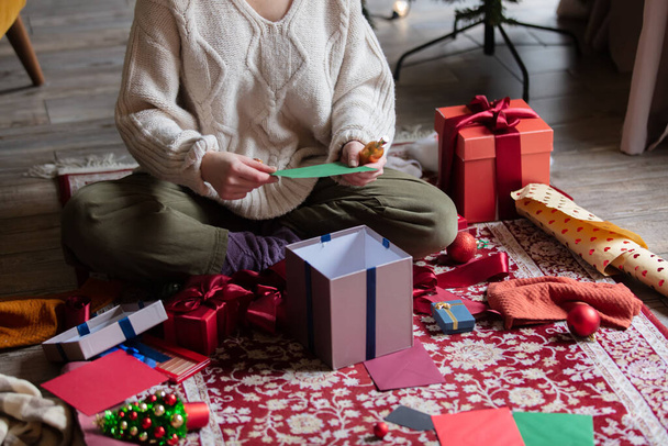 Donna che avvolge regali di Natale a casa su un piano. - Foto, immagini