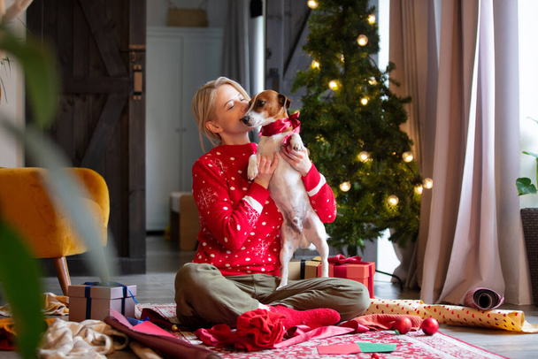 Woman wrapping Christmas gifts at home on a floor. - 写真・画像