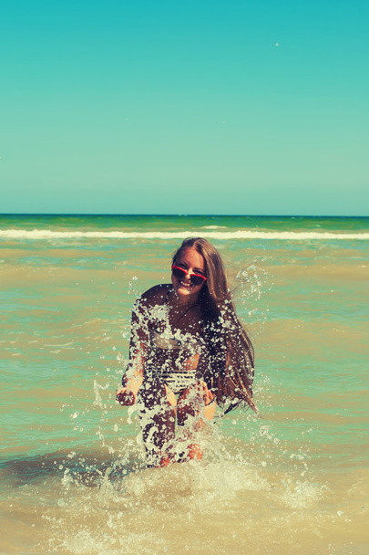 Young girl in the sea water splashes and smiling - Photo, Image