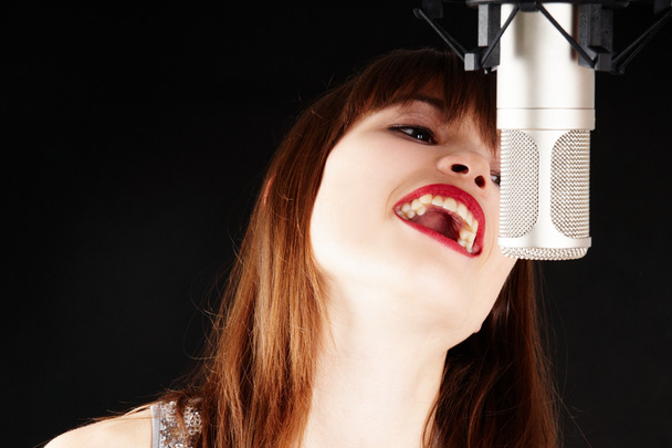 Girl singing to the microphone in a studio - Fotoğraf, Görsel