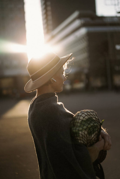Beautiful middle-aged woman in a hat with a short haircut in the center of a big city. Close-up portrait, soft backlight. - Foto, Bild