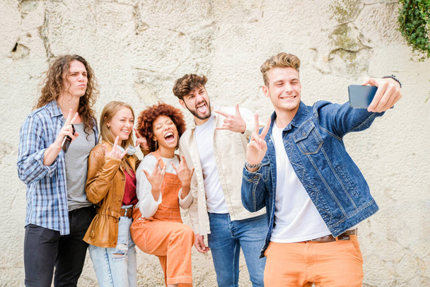 Szczęśliwi młodzi ludzie robiący selfie w mieście - Wielorasowa grupa przyjaciół robi zdjęcie patrząc w kamerę - Zdjęcie, obraz