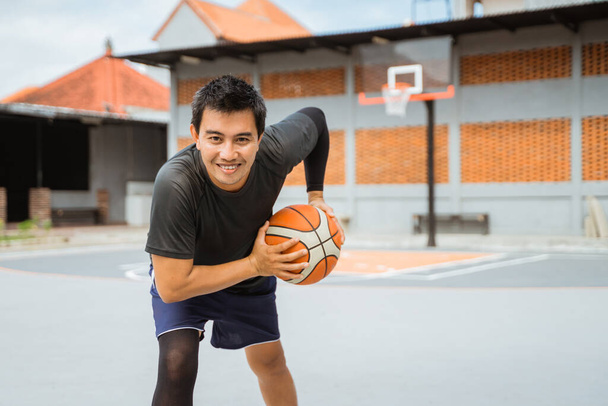 a basketball player holding a basketball in a pose holding the ball while dribbling - Foto, Bild