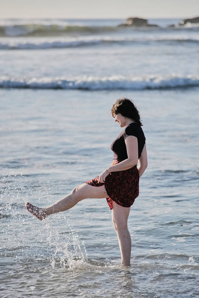Genç kız sahilde ayaklarını ıslatıyor. - Fotoğraf, Görsel