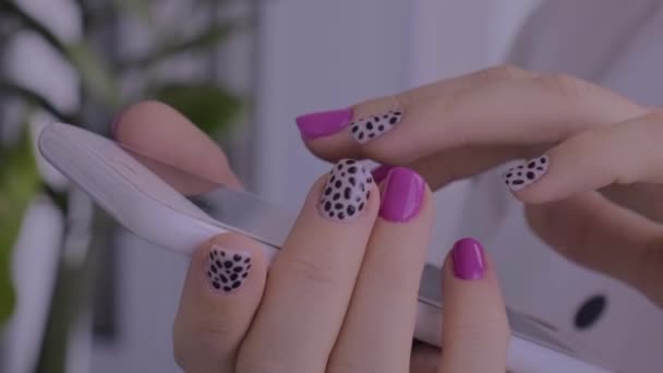 Manicure kobiece ręce ze stylowymi różowymi paznokciami trzymając telefon komórkowy. Technologia smartfona. Modny nowoczesny design manicure. Gwoździe żelowe. Skóra. Zabieg kosmetyczny. Opieka nad paznokciami. Modne kolory - Materiał filmowy, wideo