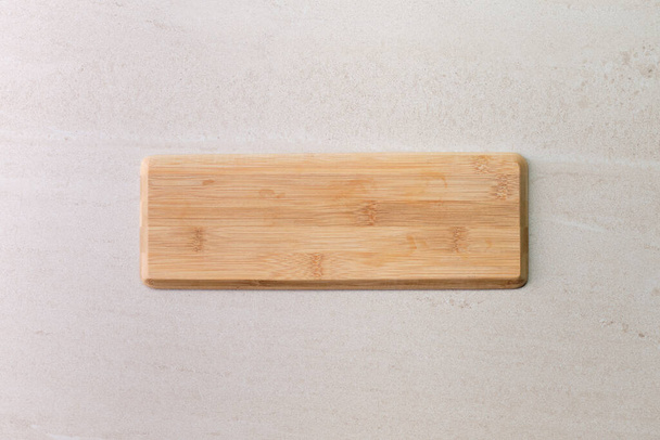Wooden board on old beige marble surface. Top view with copy space for product or text. - Foto, immagini