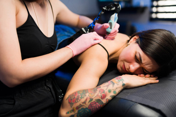 Esto duele mucho. Hermosa mujer sufriendo y con dolor mientras se hace un nuevo tatuaje  - Foto, Imagen