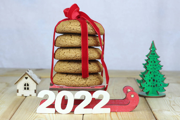 2022, ein Symbol für das nahende neue Jahr, ein Stapel selbst gebackener Lebkuchen auf einem kleinen Schlitten. Konzeptioneller Hintergrund des Urlaubs. - Foto, Bild