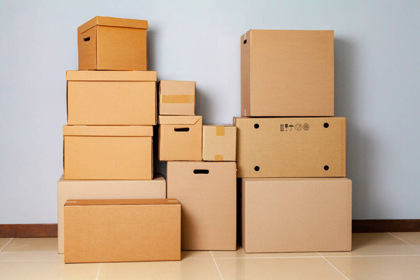 Cardboard boxes for moving on the floor against grey wall - Φωτογραφία, εικόνα