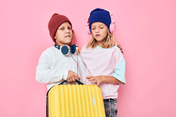 Muotokuva tyttö ja poika valmistautuu loma nuoret matkustajat vaaleanpunainen väri tausta - Valokuva, kuva
