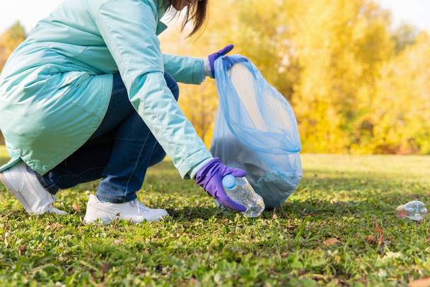 A female volunteer cleans plastic garbage in nature. - Fotoğraf, Görsel