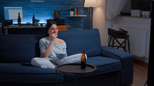 Расслабься женщина в пижаме, ест попкорн перед телевизором, - Фото, изображение