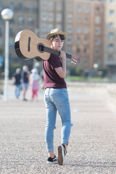 ギターを肩に持つ可愛い10代の音楽家の肖像 - 写真・画像